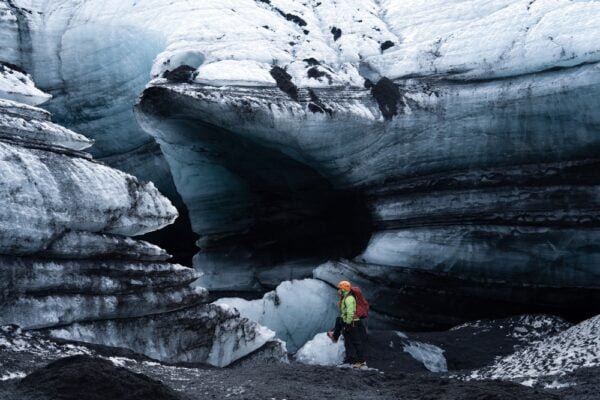 Woman inside a melting glacier ice cave. Beauty of Katla Ice Cave, where the natural wonder of ice formations and crystal-clear light combine to create an unforgettable experience
