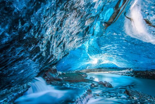 Blue crystal ice cave and an underground river beneath the glacier in Iceland